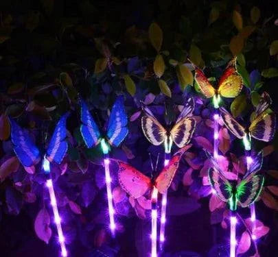 Stand alone solar-powered butterfly garden lights in purple, green, and orange hues at night